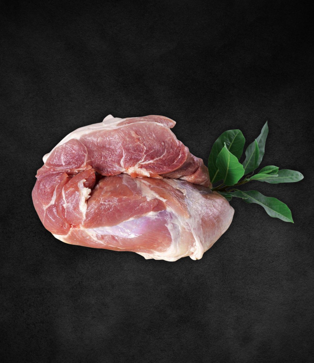 Spalla/Polpa di suino di Corte Preziosa, taglio tenero con venature di grasso e foglie fresche accanto.